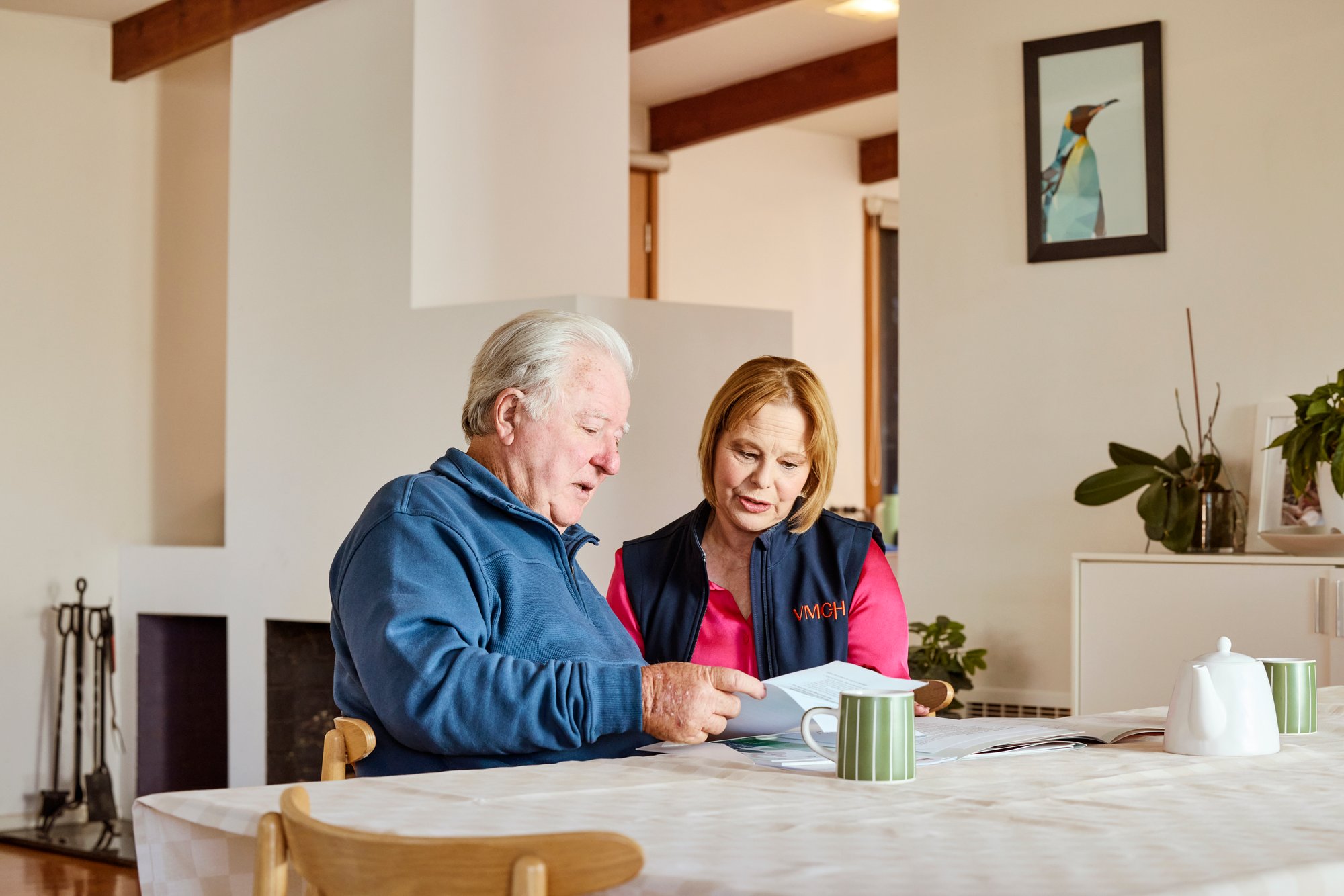 An older man sitting at a table with a VMCH support worker looking at paperwork