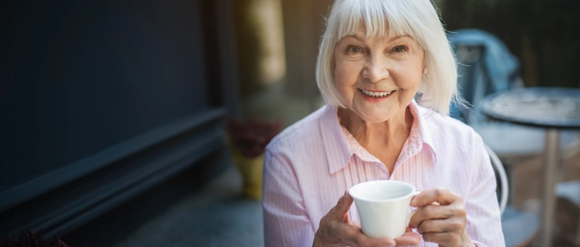 Elderly woman holding a teacup and smiling