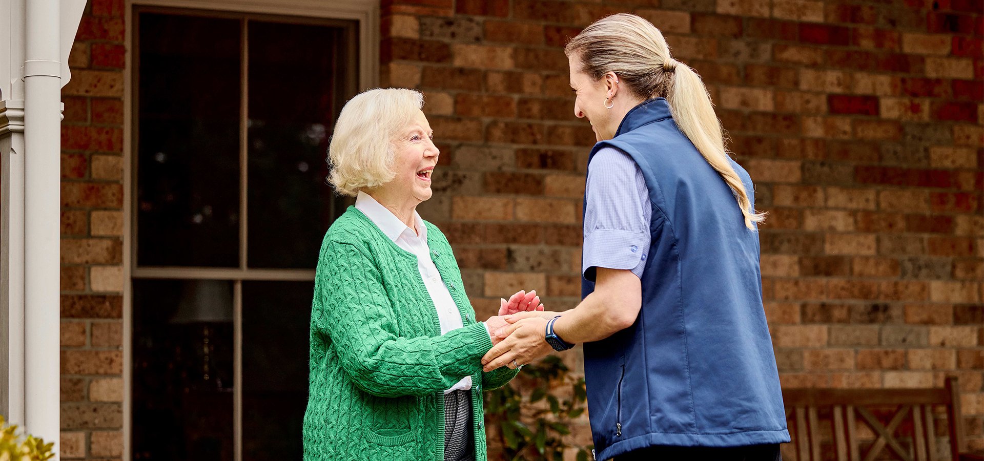 Older woman in green cardigan greeting a VMCH staff member