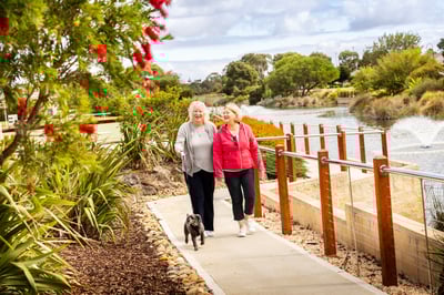 Two elderly women walking their dog outside